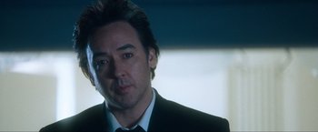 Movie still from “War, Inc.” (2008), directed by Joshua Seftel – A person wearing a suit and tie; Close Up shot, Low angle