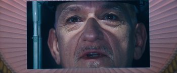Movie still from “War, Inc.” (2008), directed by Joshua Seftel – An older man with a beard and mustache looking at the camera; Extreme Close Up shot, Low angle