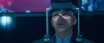Movie still from “War, Inc.” (2008), directed by Joshua Seftel – An older man wearing a helmet with a microphone attached to it's head; Close Up shot, Over the shoulder angle