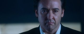Movie still from “War, Inc.” (2008), directed by Joshua Seftel – A person wearing a suit and tie; Close Up shot, Low angle