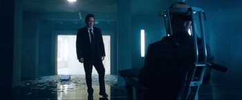 Movie still from “War, Inc.” (2008), directed by Joshua Seftel – A man wearing a suit and tie standing in front of a mirror; Wide shot, Low angle