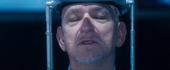 Movie still from “War, Inc.” (2008), directed by Joshua Seftel – An older man wearing a hard hat with his eyes closed; Extreme Close Up shot, Over the shoulder angle