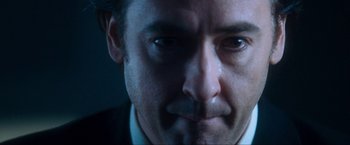 Movie still from “War, Inc.” (2008), directed by Joshua Seftel – A man's face in a dark room; Close Up shot, Low angle
