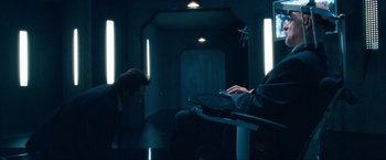 Movie still from “War, Inc.” (2008), directed by Joshua Seftel – A man sitting in a room with a laptop; Wide shot, High angle