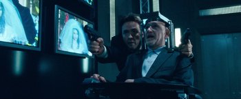 Movie still from “War, Inc.” (2008), directed by Joshua Seftel – Two men in suits are playing a video game; Medium shot, Over the shoulder angle