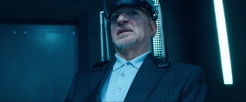 Movie still from “War, Inc.” (2008), directed by Joshua Seftel – An older man wearing a suit and a helmet; Close Up shot, Low angle