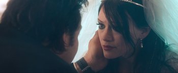 Movie still from “War, Inc.” (2008), directed by Joshua Seftel – A woman looking into a mirror while a man looks on; Close Up shot, Over the shoulder angle