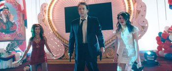 Movie still from “War, Inc.” (2008), directed by Joshua Seftel – A man in a suit and tie holding a gun; Medium shot, Low angle