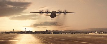 Movie still from “War, Inc.” (2008), directed by Joshua Seftel – An airplane is flying in the air at sunset; Extreme Wide shot, Low angle