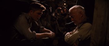 Movie still from “Water for Elephants” (2011), directed by Francis Lawrence – Two men sitting in a room with people in the background; Medium shot, High angle