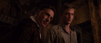 Movie still from “Water for Elephants” (2011), directed by Francis Lawrence – A man standing next to another man in a dark room; Close Up shot, Over the shoulder angle