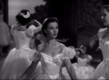 Movie still from “Waterloo Bridge” (1940), directed by Mervyn LeRoy – A black and white photo of a woman in a ball gown; Medium shot, Low angle
