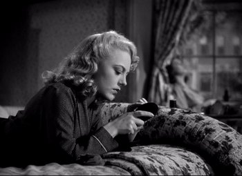 Movie still from “Waterloo Bridge” (1940), directed by Mervyn LeRoy – A black and white photo of a woman looking at her cell phone; Medium shot, Low angle