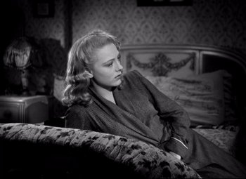 Movie still from “Waterloo Bridge” (1940), directed by Mervyn LeRoy – A black and white photo of a woman sitting on a couch; Medium shot, High angle