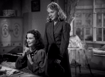 Movie still from “Waterloo Bridge” (1940), directed by Mervyn LeRoy – Two women standing next to each other in front of a table; Medium shot, Low angle