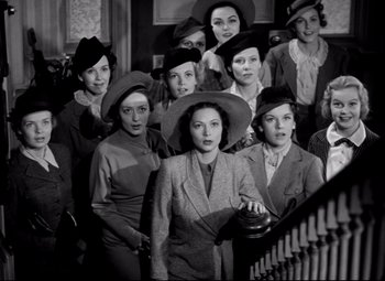 Movie still from “Waterloo Bridge” (1940), directed by Mervyn LeRoy – A group of women wearing hats posing for a picture; Medium shot, Low angle