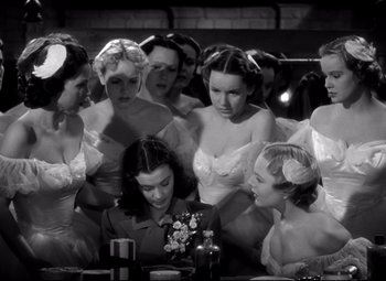 Movie still from “Waterloo Bridge” (1940), directed by Mervyn LeRoy – A group of women standing next to each other in a room; Medium shot, High angle