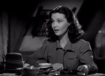 Movie still from “Waterloo Bridge” (1940), directed by Mervyn LeRoy – A black and white photo of a woman sitting at a table; Close Up shot, High angle