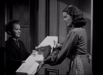 Movie still from “Waterloo Bridge” (1940), directed by Mervyn LeRoy – A woman is handing a box to another woman; Medium shot, High angle