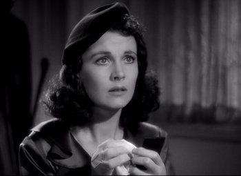 Movie still from “Waterloo Bridge” (1940), directed by Mervyn LeRoy – A woman in a hat holding a donut in her hands; Close Up shot, High angle