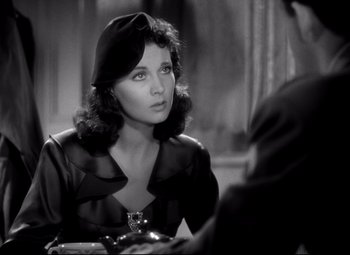 Movie still from “Waterloo Bridge” (1940), directed by Mervyn LeRoy – A black - and - white photo of a woman sitting at a table; Close Up shot, Over the shoulder angle