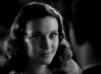 Movie still from “Waterloo Bridge” (1940), directed by Mervyn LeRoy – A young woman is smiling for the camera; Close Up shot, Over the shoulder angle