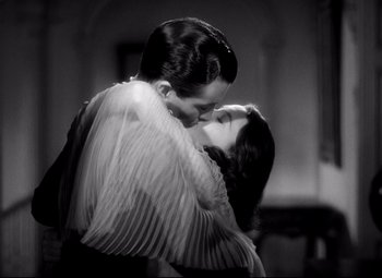Movie still from “Waterloo Bridge” (1940), directed by Mervyn LeRoy – A man and a woman kissing each other in front of a wall; Medium shot, Low angle