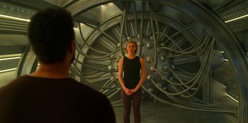 Movie still from “Another Life” (2019), created by Aaron Martin – A woman standing in front of a wall with wires on it; Wide shot, Over the shoulder angle