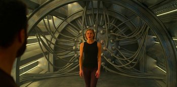Movie still from “Another Life” (2019), created by Aaron Martin – A woman standing in front of a wall with wires; Wide shot, Low angle