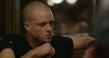 Movie still from “We Are Your Friends” (2015), directed by Max Joseph – A man with a shaved head is sitting at a table; Close Up shot, Over the shoulder angle