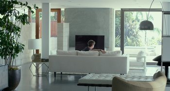 Movie still from “We Are Your Friends” (2015), directed by Max Joseph – A man sitting on a couch in front of a fire place; Wide shot, High angle