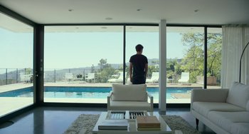 Movie still from “We Are Your Friends” (2015), directed by Max Joseph – A man standing in front of a window looking out at a pool; Wide shot, Low angle