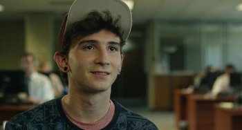 Movie still from “We Are Your Friends” (2015), directed by Max Joseph – A young man wearing a baseball cap and a shirt; Close Up shot, Over the shoulder angle