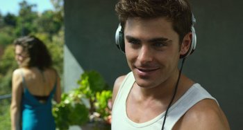Movie still from “We Are Your Friends” (2015), directed by Max Joseph – A young man wearing a white tank top while listening to headphones; Close Up shot, Over the shoulder angle