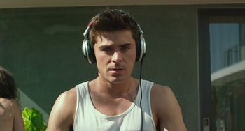 Movie still from “We Are Your Friends” (2015), directed by Max Joseph – A young man wearing headphones while standing in front of a wall; Close Up shot, Over the shoulder angle