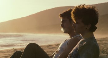 Movie still from “We Are Your Friends” (2015), directed by Max Joseph – A man and a woman sitting on the beach; Medium shot, Over the shoulder angle