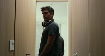 Movie still from “We Are Your Friends” (2015), directed by Max Joseph – A man with headphones standing in front of a door; Medium shot, Over the shoulder angle
