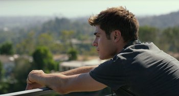 Movie still from “We Are Your Friends” (2015), directed by Max Joseph – A man sitting on top of a building looking out a window; Close Up shot, Low angle