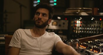 Movie still from “We Are Your Friends” (2015), directed by Max Joseph – A man sitting in a room with a glass of beer; Close Up shot, Over the shoulder angle