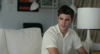 Movie still from “We Are Your Friends” (2015), directed by Max Joseph – A man in a white shirt sitting on a couch; Medium shot, Over the shoulder angle