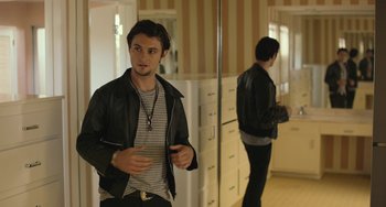 Movie still from “We Are Your Friends” (2015), directed by Max Joseph – A man in a black leather jacket standing in a kitchen; Medium shot, Over the shoulder angle
