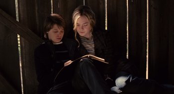 Movie still from “We Bought a Zoo” (2011), directed by Cameron Crowe – A woman and a boy sitting on the ground reading a book; Medium shot, High angle