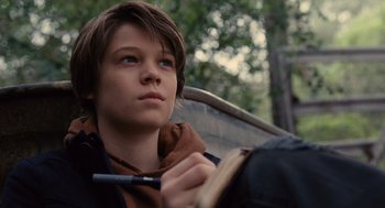 A young boy is writing on a book