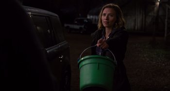Movie still from “We Bought a Zoo” (2011), directed by Cameron Crowe – A woman holding a bucket in front of a parked car; Medium shot, Over the shoulder angle