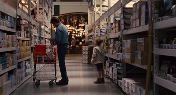 Movie still from “We Bought a Zoo” (2011), directed by Cameron Crowe – A man and a child are in a store; Wide shot, Over the shoulder angle