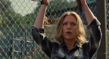 Movie still from “We Bought a Zoo” (2011), directed by Cameron Crowe – A woman holding a pair of scissors behind a chain link fence; Close Up shot, Low angle