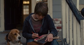 Movie still from “We Bought a Zoo” (2011), directed by Cameron Crowe – A young man sitting on the ground writing on a notebook; Medium shot, Over the shoulder angle