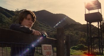 Movie still from “We Bought a Zoo” (2011), directed by Cameron Crowe – A young boy leaning on a fence looking at a mountain; Medium shot, Low angle