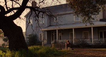 Movie still from “We Bought a Zoo” (2011), directed by Cameron Crowe – A woman sitting on the ground in front of a house; Extreme Wide shot, Low angle