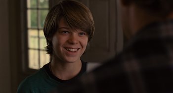 Movie still from “We Bought a Zoo” (2011), directed by Cameron Crowe – A young man smiling at the camera while wearing a green t - shirt; Close Up shot, Over the shoulder angle
